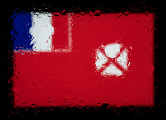 Flag of Wallis and Futuna. Abstract photo with water drops on glass. Isolated on black background.