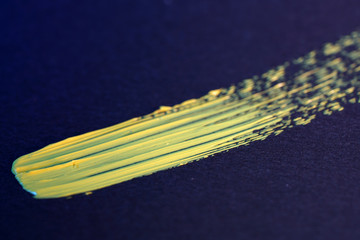 Yellow green oil paint freshly photographed from the tube for artists with brush on black background