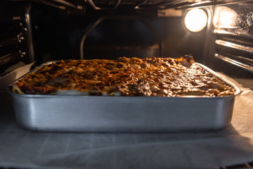 Close-up of a traditional lasagna made with minced beef bolognese sauce in a baking tray in oven