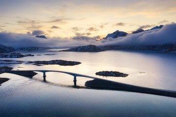 View from the air on the bridge and mountains during sunset. Lofoten Islands, Norway. Landscape from the drone. Panorama of mountains, roads and ocean.
