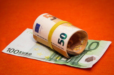 eine Rolle mit Fünfzigern liegt auf einer Einhundert Euronote