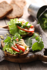 Healthy food. Bread with cream cheese, herbs, lettuce, tomatoes and pumpkin seeds on a grey wooden background. Rustic. Background image, copy space