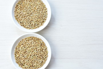 Seed of birdseed, food for birds, displayed in containers on white wooden background