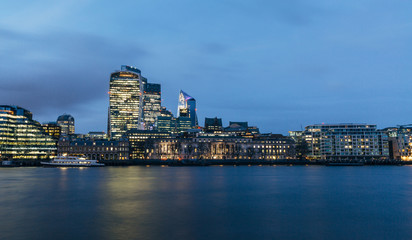 Naklejka premium View of London downtown skyline with skyscrapers reflection in river Thames. Long exposure blue hour shot.