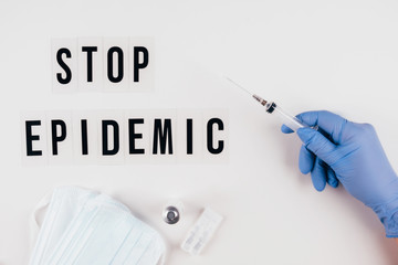 The words STOP EPIDEMIC on a gray background and a gloved hand with a syringe.