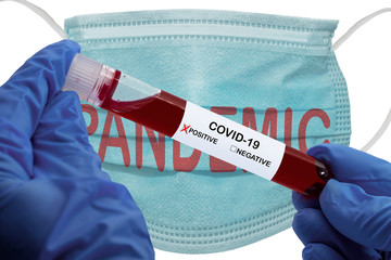 Hands holding blood sample in vacuum tube with Positive Coronavirus analysis COVID-19, over medical mask with the text PANDEMIC