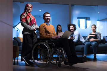 Handicapped young man with colleagues working in office. He is smiling and passionate about the workflow. Performing in co-working space. Office people working together.