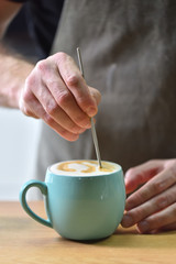 Bartender in a coffee shop, creates a picture while making coffee, closeup
