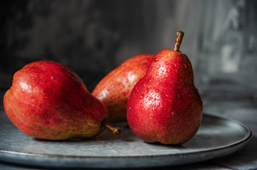 ripe red pear fruits with water drops on gray plate