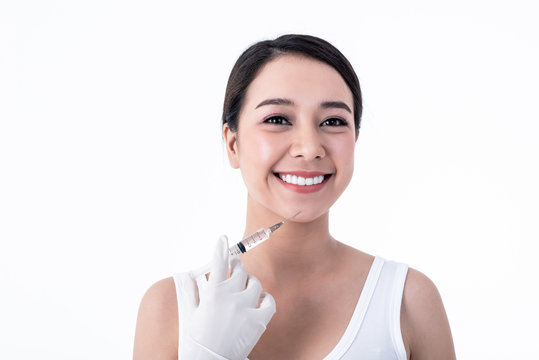 Portrait images of Asian pretty young woman, smiling, beautiful white and clean teeth And syringe placed on the face Ready for injection On white background to people and Cosmetic surgery concept.