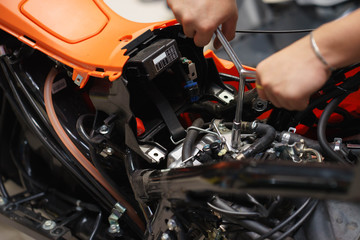 Mechanic using a wrench and socket on the engine of a motorcycle , selective focus