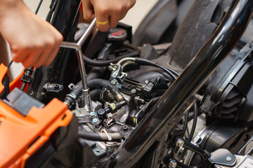 Mechanic using a wrench and socket on the engine of a motorcycle , selective focus