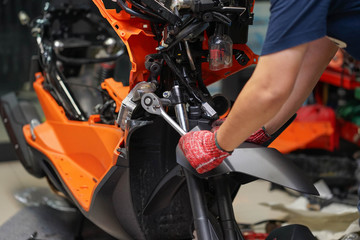 Fototapeta na wymiar Mechanic using a wrench and socket on the engine of a motorcycle , selective focus