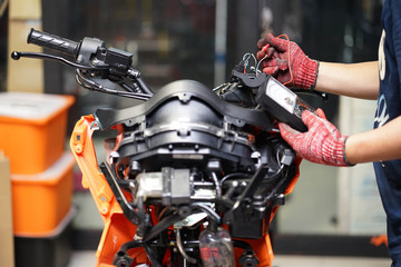 An auto mechanic uses a multimeter voltmeter to check the voltage level in a motorcycle , selective...