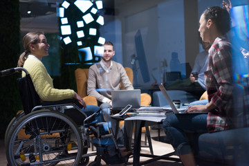 Handicapped young woman with colleagues working in office. She is smiling and passionate about the workflow. Performing in co-working space. Office people working together.