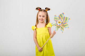 happy baby girl with long hair smiling and holding a baby windmill on a white background