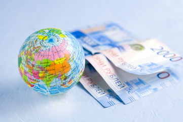 A bundle of bills, a globe. The concept of a financial crisis or recovery.