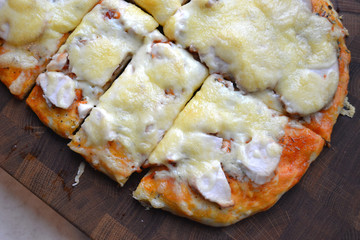 Tasty hot slice of pizza on a wooden board with melting cheese. Rustic pizza concept.