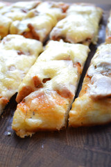 Tasty hot slice of pizza on a wooden board with melting cheese. Rustic pizza concept.