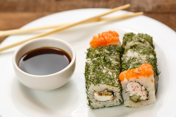A set of rolls with dill and salmon on a plate with soy sauce and chopsticks. Horizontal frame