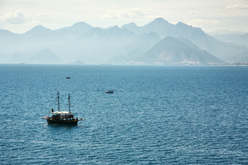 tourist sailing ship in a bay on background of mountains.