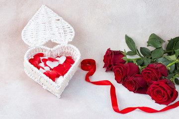 heart-shaped box with satin roses, a bouquet of five roses and a red satin ribbon