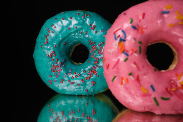 Blue and pink Donuts isolated on a black background. Close up.