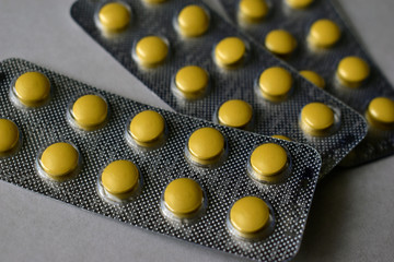 A bunch of white and yellow tablets in blisters on a white background