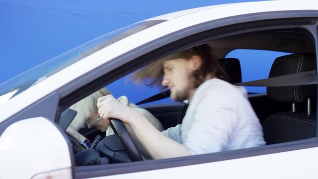 Brunette man and blonde woman get into an accident while travelling by car against chroma key background. They are shocked and puzzled. Angry driver opens his car door and yells at culprit of the