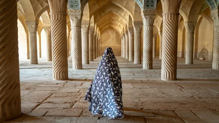Fototapeten Unidentified woman walking in prayer hall of Vakil Mosque with columns, Shiraz, Iran © CanYalicn