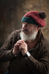 Studio portrait of handsome mature stylish man with beard and mustache dressed in warm knitted clothes, selective focus