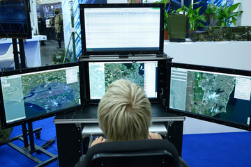 Young man sitting in front of monitors and working with military computer-assisted dispatch station...