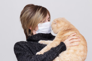 Cute girl with a cat, wearing a health mask, isolated in the background, flu epidemic, dust Allergy, virus protection. Concept of air pollution in the city, close- up