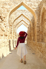 Fototapeta na wymiar Female Visitor Walking along the Iconic Archways of Ancient Bahrain Fort in Manama, Bahrain