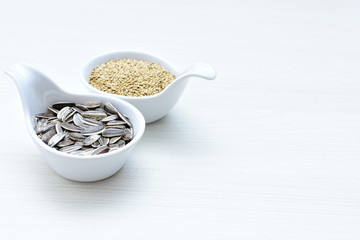 Birdseed and natural sunflower seeds, food for birds, displayed in containers on white wooden background