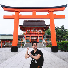 Traveler in front of the Great Torii gate and the Romon Gate at Fushimi Inari taisha shrine, Kyoto,...
