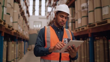 Portrait of a warehouse worker using digital tablet while looking at warehouse storage area - Powered by Adobe