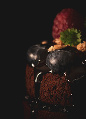 Czekoladowe babeczki z malinami i jagodami na czarnym tle, zamykają w górę widoku, Karmowa fotografia z jaskrawymi kolorami - 329643414