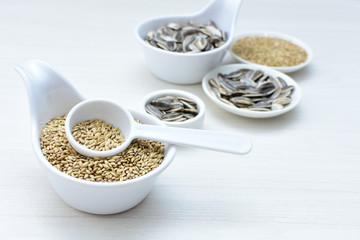 Birdseed and natural sunflower seeds, food for birds, displayed in containers on white wooden background