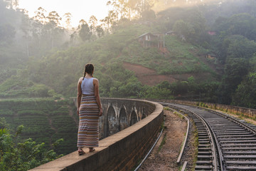 Young woman walking on the Famous Nine Arch Bridge in Demodara, Sri Lanka during sunrise