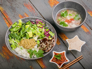 Organic asian healthy food. Buddha bowl with salmon fish soup, salad, rice with pesto, spinach leaves, green beans, beef with teriyaki sauce. Close up
