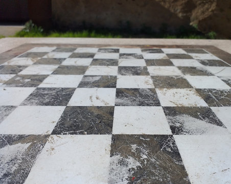 Perspective image of floor with black and white tiles. Chess board made of stone. Old picture.