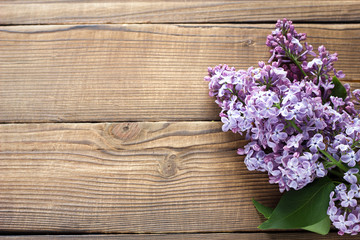 Naklejka na ściany i meble branch of purple lilac on a wooden background. Spring flowers on a wooden background with a place under the inscription