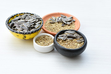 Birdseed and natural sunflower seeds, food for birds, displayed in containers on white wooden background