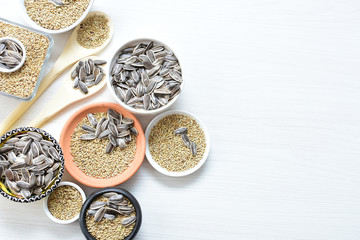 Fototapeta na wymiar Birdseed and natural sunflower seeds, food for birds, displayed in containers on white wooden background