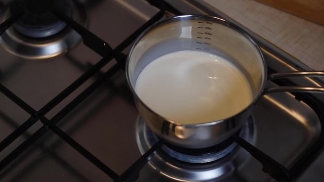 A stewpan with milk is placed on a burning gas stove