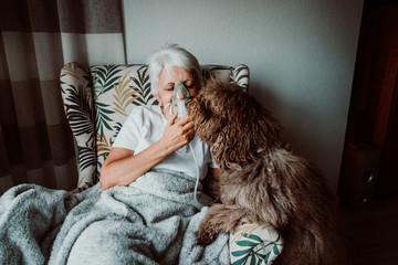 White-haired middle-aged woman with medical treatments at home. Assisted breathing to eliminate...