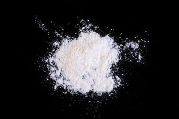 Obraz na płótnie Canvas White wheat flour scattered on black glass.