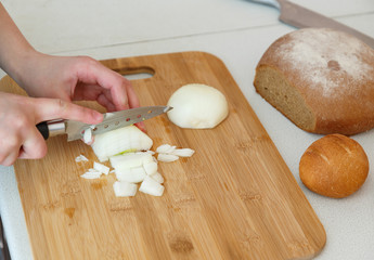 cutting white onions on a blackboard on a white kitchen table