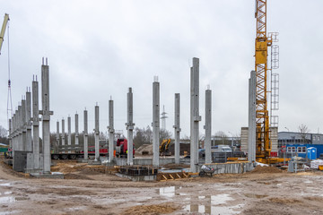a large construction site many concrete columns are placed with the help of a crane
